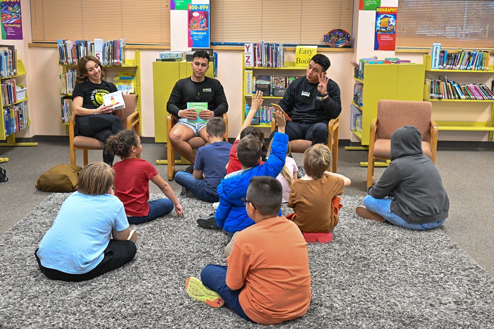 Three staff members read to a group of students