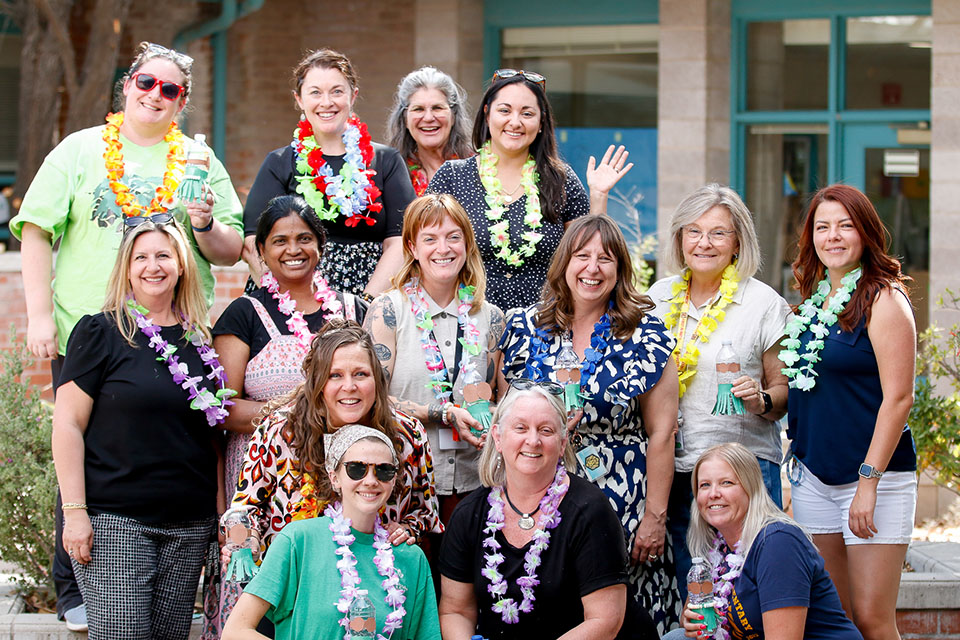 A group of teachers smile in their leis and luau gear