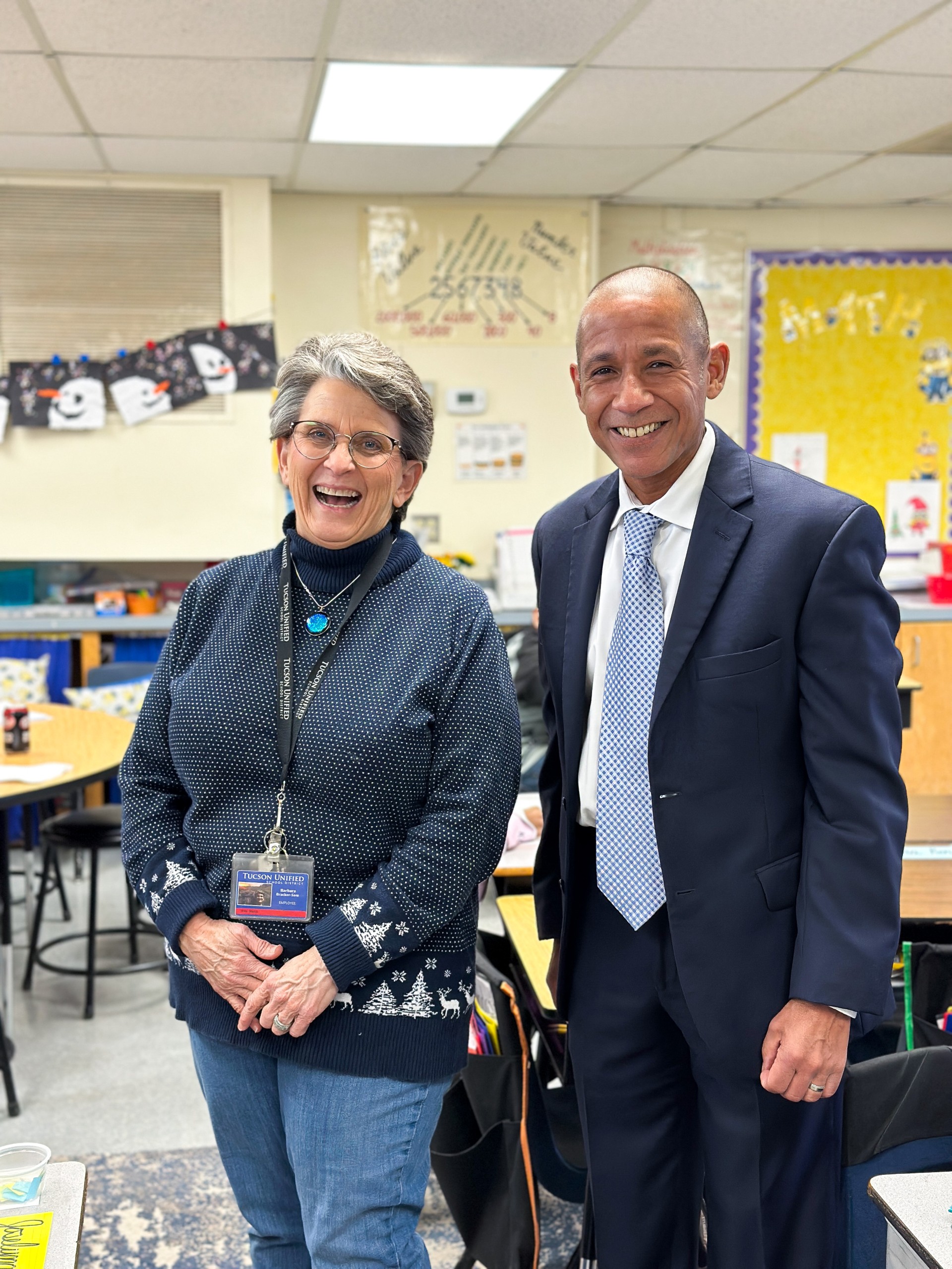 A woman in a blue sweater smiles next to a man in a blue suit