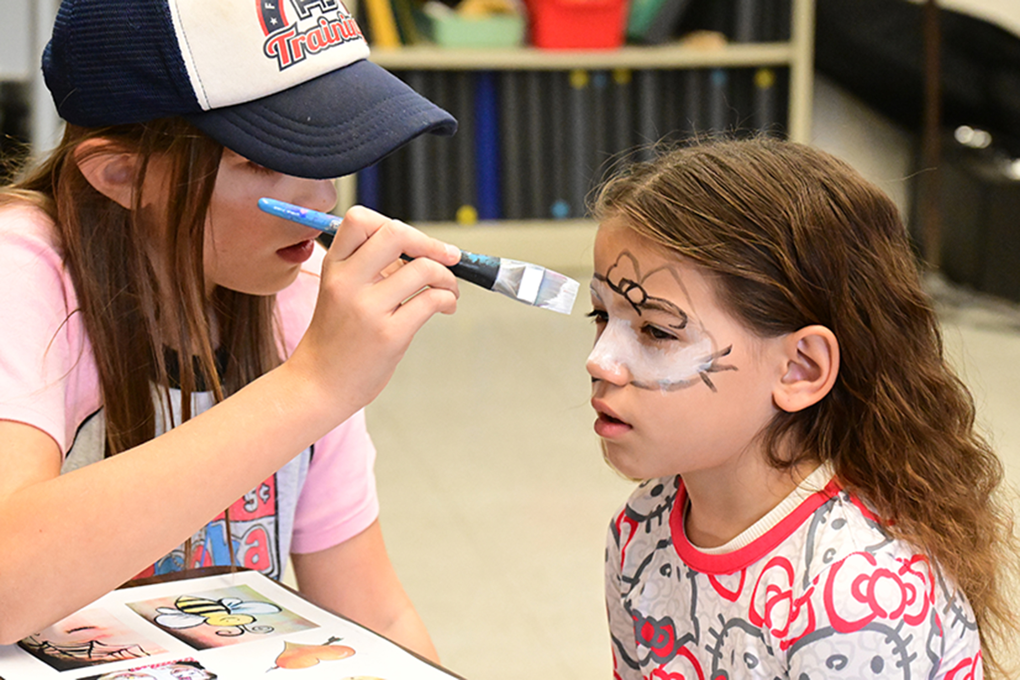A woman paints a little girl's face