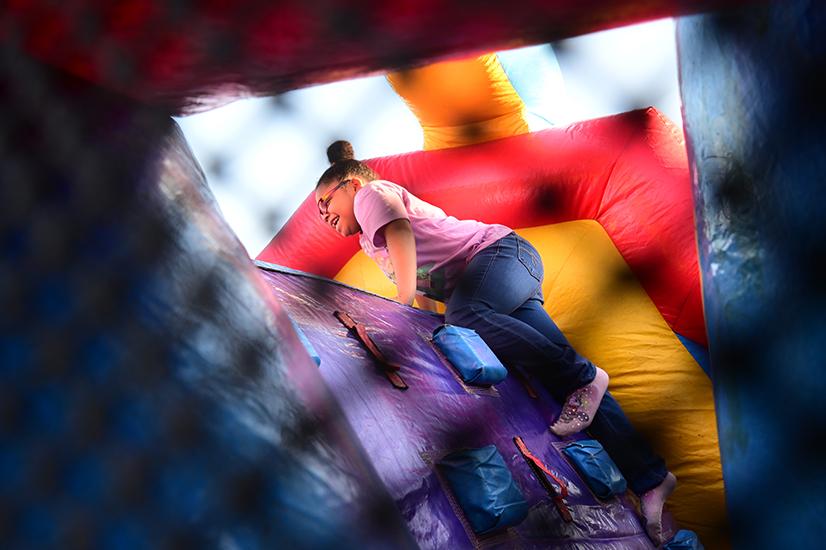A girl climbs up on a bouncy house
