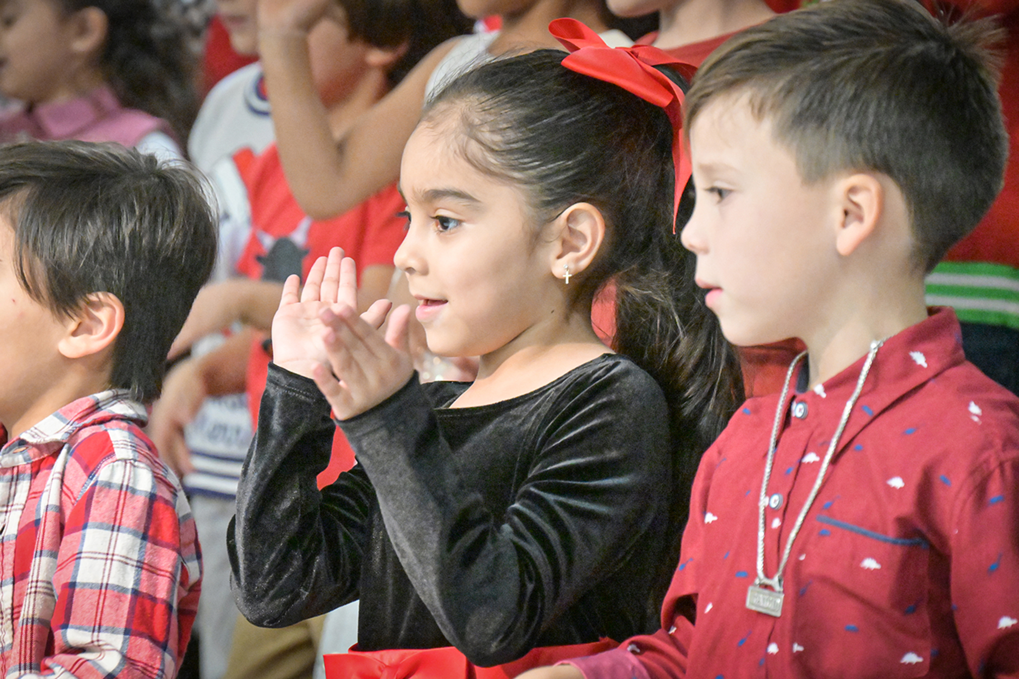 A little girl claps her hands as she and her classmates perform a song