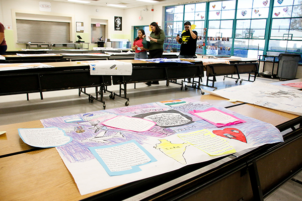 A student made presentation on a poster board, front, with a family looking at other projects in the background
