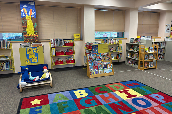 A colorful alphabet rug with bookshelves in the background