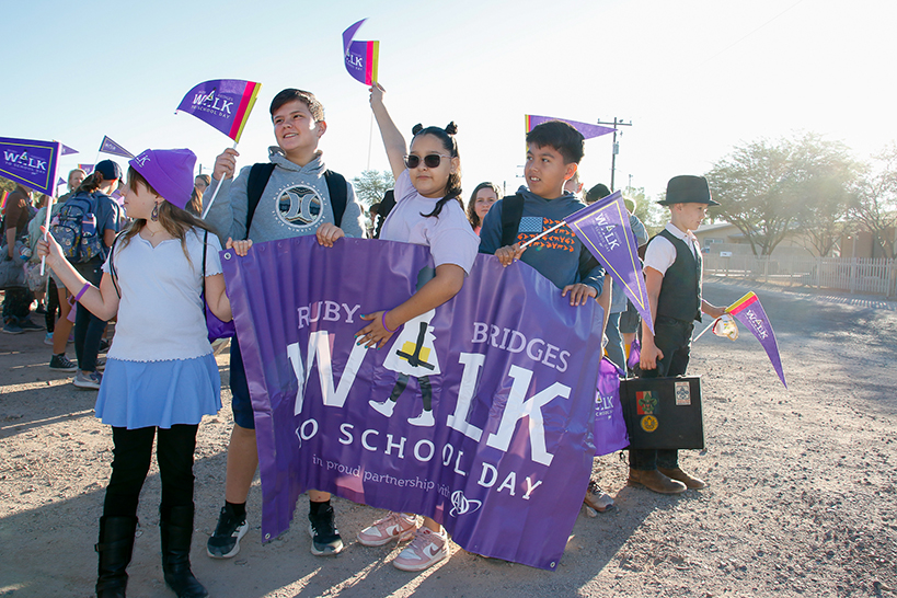 Students hold up a purple Ruby Bridges Walk to School Day banner and pennants