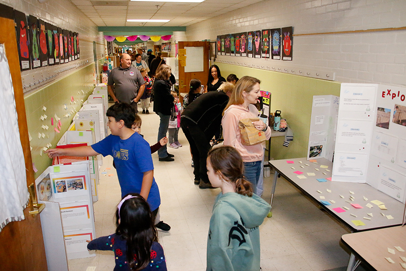 Students peruse science fair projects in the hallway