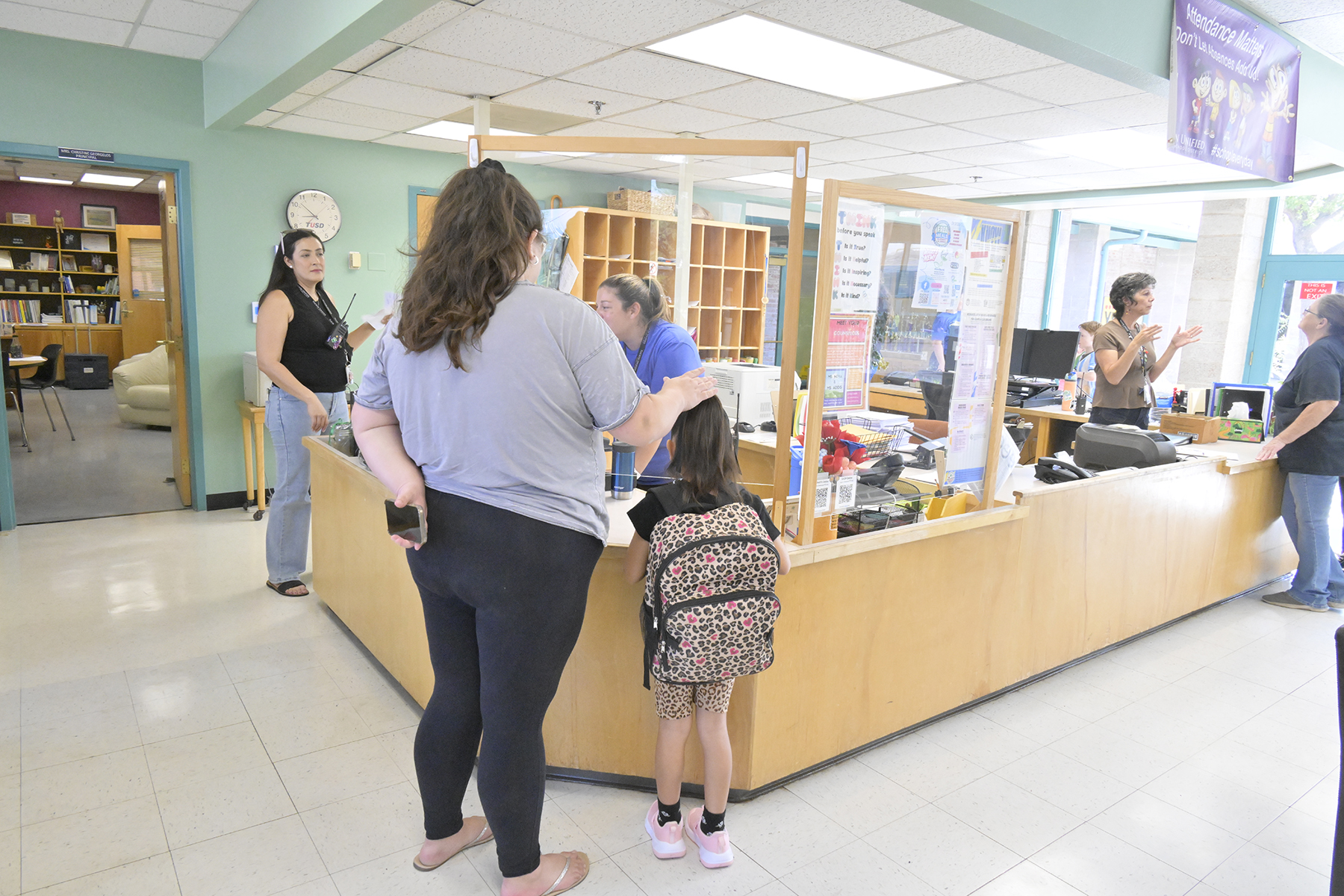 A mom and her daughter talk to the front office staff