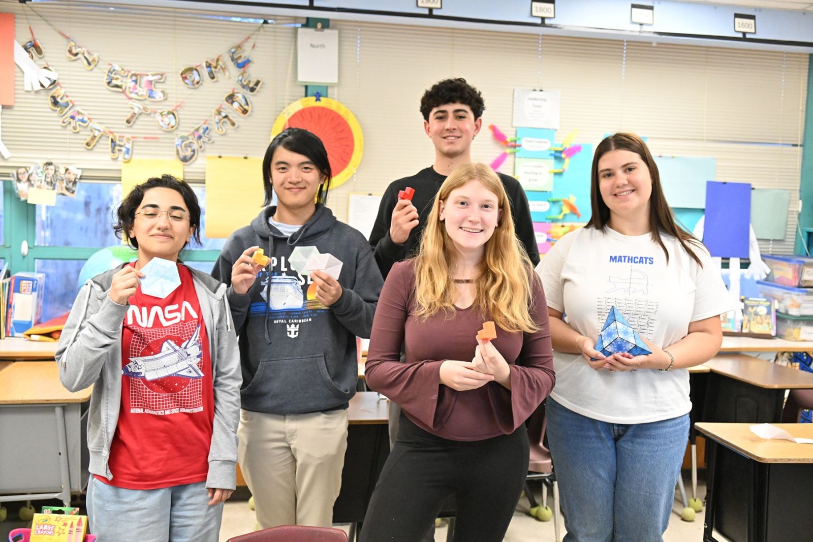 A group of students holds up their paper creations.